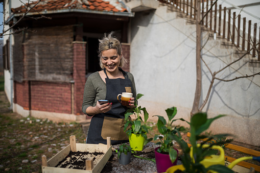 Happy woman using smartphone and drinking coffee