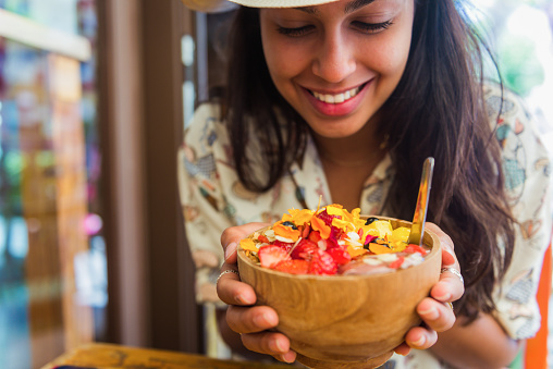 Beautiful girl holding bowl with a fruit salad and edible flowers