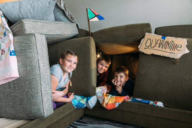 Children in Couch Fort Young siblings, who are under a shelter in place order, are having fun in a couch fort quarantine. They are enjoying time playing at home. One good by product of a pandemic. fort stock pictures, royalty-free photos & images