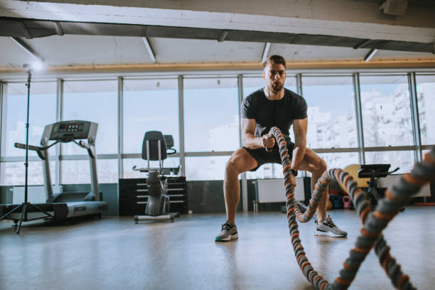istock Young man practicing with battle ropes in the gym 1216182779