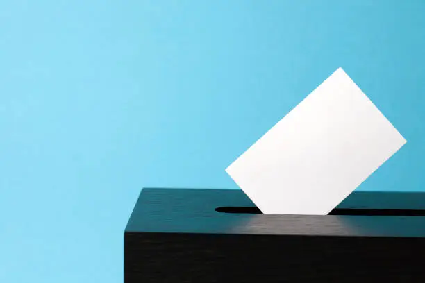 ballot box with voting paper in hole.