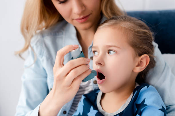 fürsorgliche mutter hält inhalator in der nähe von asthmatischen tochter - asthmainhalator stock-fotos und bilder