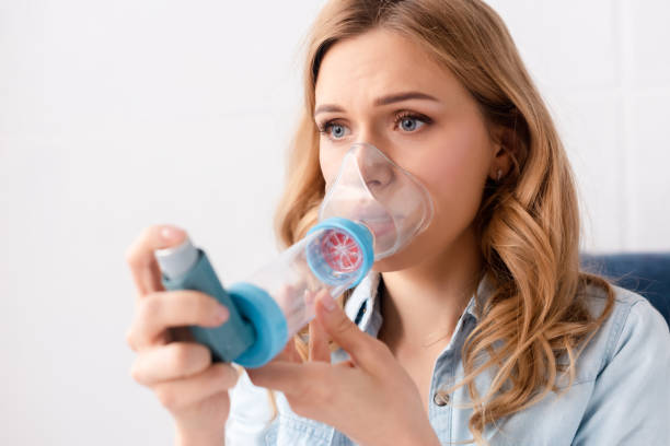 enfoque selectivo de mujer asmática usando inhalador con espaciador - inhalador de asma fotografías e imágenes de stock