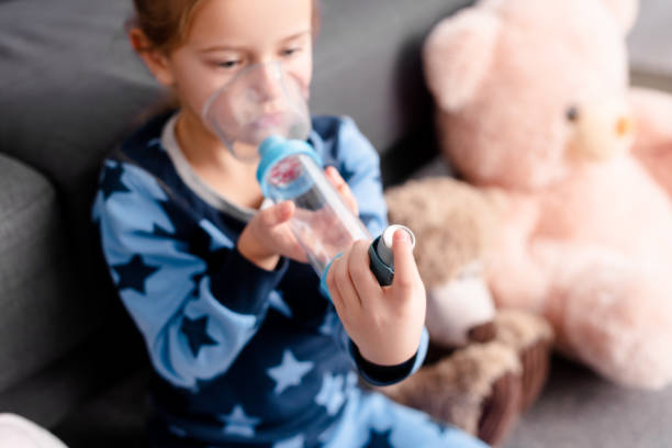 부드러운 장난감 근처 스페이서 흡입기를 사용하여 아픈 아이의 선택적 초점 - 천식 호흡기 뉴스 사진 이미지