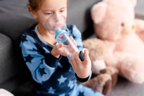 selektywne skupienie chorego dziecka za pomocą inhalatora z podkładką dystansową w pobliżu miękkich zabawek - asthma inhaler zdjęcia i obrazy z banku zdjęć