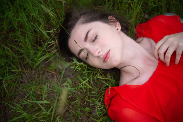 Above shot of girl lying in a green wheat field and enjoys the nature