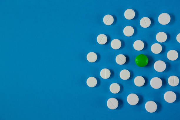 istock many white pills and one green on a blue background 1216187258