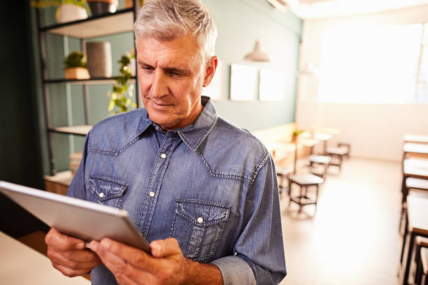 istock Mature man working on a tablet in his coffee shop 1216189836