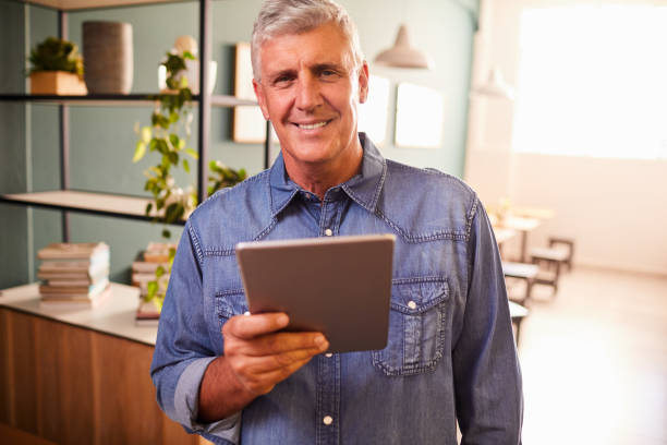 istock Smiling mature man working on a tablet in his coffee shop 1216190187