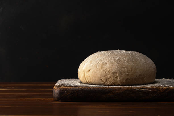 istock Fresh raw dough for bread or pizza with eggs on a dark wooden table. 1216191604
