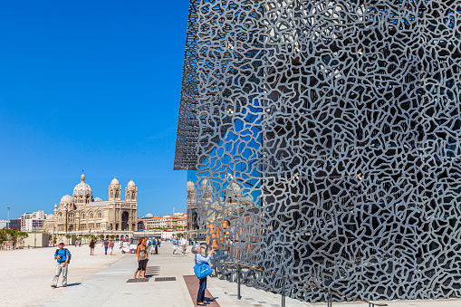 Tourists strolling next to the MuCEM, the Museum of European and Mediterranean Civilisations dedicated to the sea and its people, created for the Marseille's year as European Capital of Culture. The Cathedral of Sainte-Marie-Majeure in background.