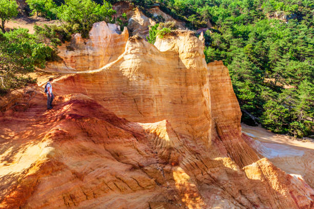 Tourist visiting the Colorado Provencal, a nature reserve with rock pinnacles and rocky hills of fantastic colors, located in the Provence-Alpes-Côte d'Azur region, in southeastern France.