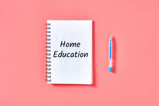 istock Notepad with words home education near pen on pink desk 1216196808