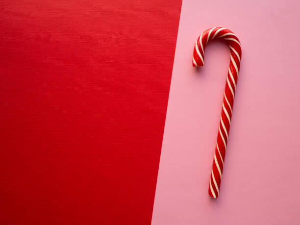 istock Striped red and white New Year's candy cane on a red-pink double background with copy space. 1216197358