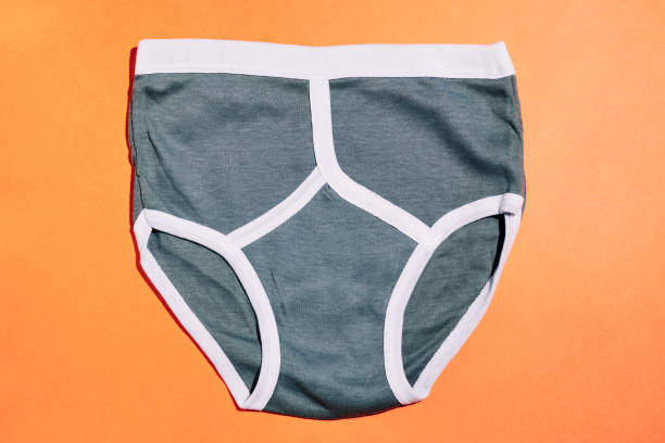 istock Single pair of Grey retro Y-front underpants against a plain orange background. 1216197428