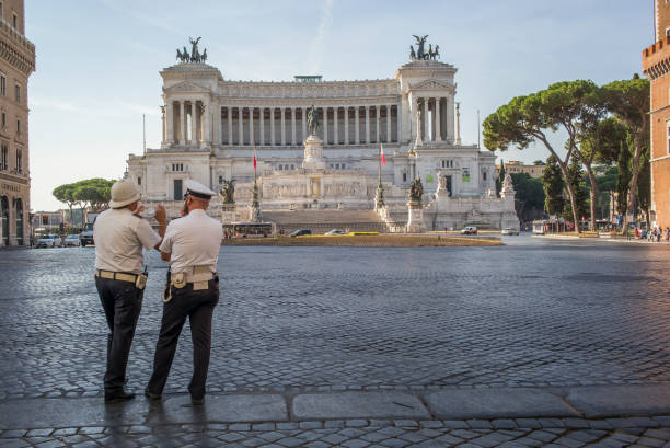 Two Italian Police soot opposite The Victor Emmanuel II National Monument or Vittoriano, improperly called Altare della Patria, is a national monument built in honour of Victor Emmanuel II, the first king of a unified Italy, located in Rome, Italy. It occupies a site between the Piazza Venezia and the Capitoline Hill