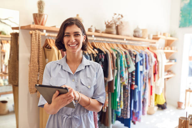 retrato de mulher dona de loja de moda verificando estoque em loja de roupas com tablet digital - empreendedor - fotografias e filmes do acervo