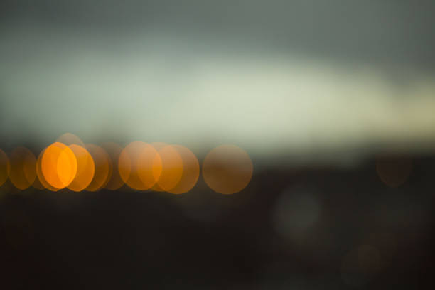 Night City gray sky, illumination. Lantern lights and windows of houses. Blurred background