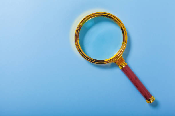 istock golden magnifier on blue paper background 1216199773