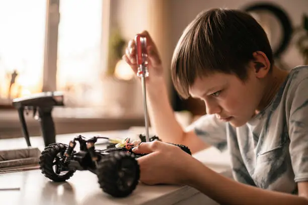 Photo of Kid boy repairs a remote controlled car  toy