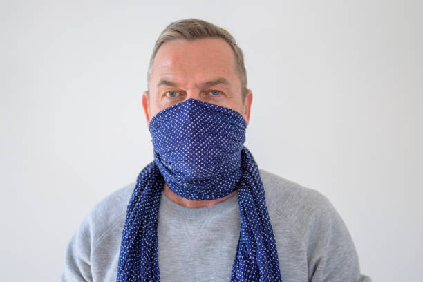 Bust portrait of man in blue scarf over his face Bust portrait of middle-aged man in blue scarf wrap over his face, used as breathing mask for protection, standing against grey background and looking at camera bandana photos stock pictures, royalty-free photos & images