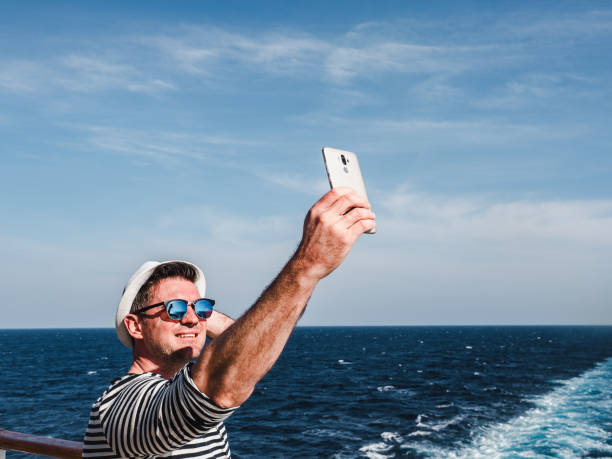 istock Fashionable man holding a mobile phone on the deck 1216206500