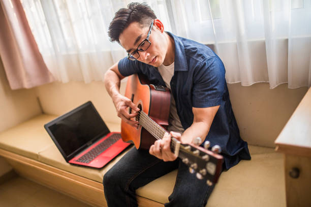 istock An Asia Chinese mature man using laptop work from home. Playing Guitar during coffee break time. 1216206513