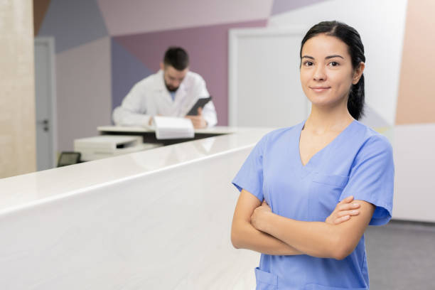 istock Happy young brunette assistant in blue uniform crossing arms by chest 1216206750