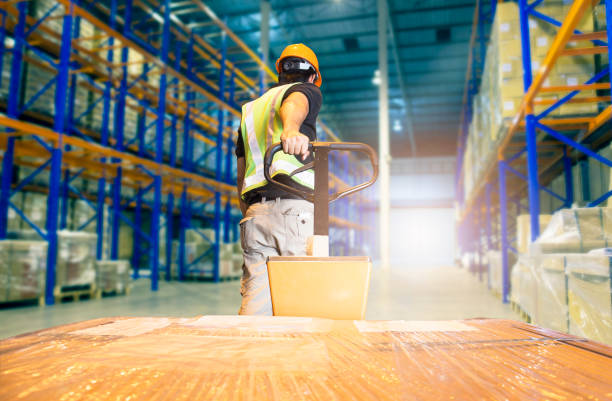 trabalhador do armazém descarregando mercadorias de embarque de paletes, interior do armazém, prateleiras altas armazenamento de mercadorias em armazenagem s - distribution warehouse forklift freight transportation pallet - fotografias e filmes do acervo