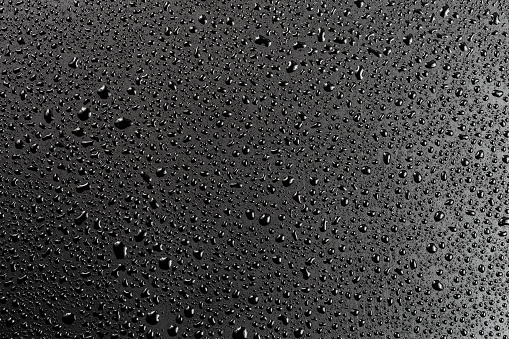 water drops on abstract flat black hydrophobic surface macro background.