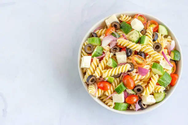 Mediterranean Fusilli Pasta Salad with Tomatoes, Black Olives, Cucumber, Mozzarella Top View Horizontal Photo with Negative Space
