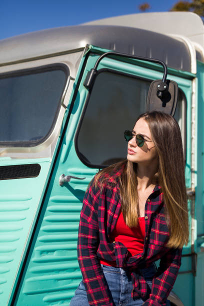 istock Smiling young woman by the vintage minivan 1216212324