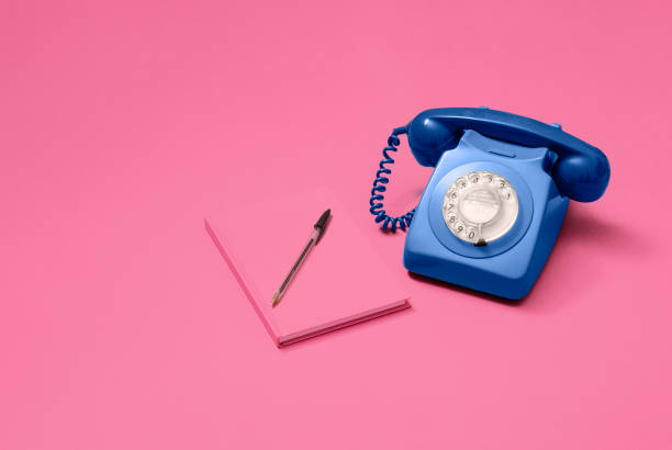 istock Blue rotary phone on pink with notebook 1216212339