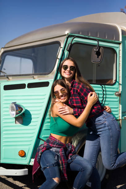 istock Smiling young women by the vintage minivan 1216212373