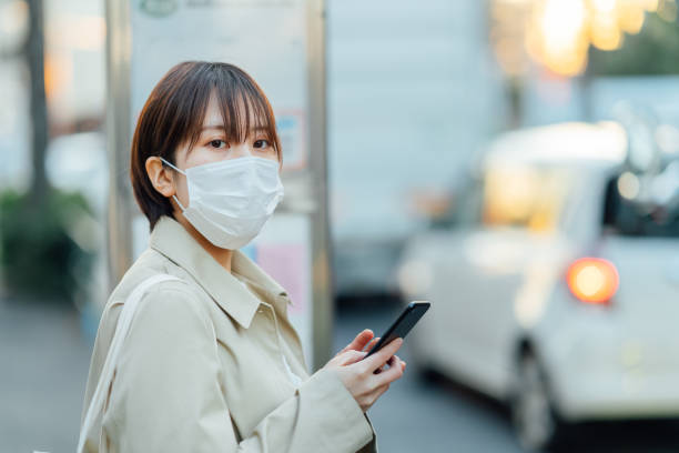 empresária usando máscara cirúrgica e esperando ônibus - rush hour commuter on the phone tokyo prefecture - fotografias e filmes do acervo