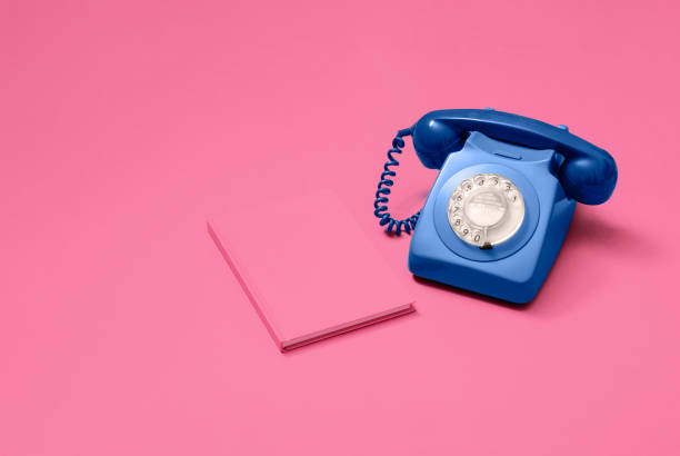 istock Blue rotary phone with pink notebook on pink 1216214113