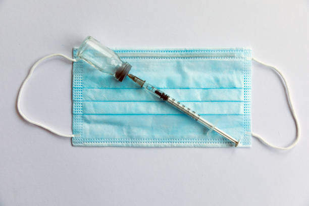 istock Disposable medical syringe, vaccine ampoule, protective mask. 1216214130