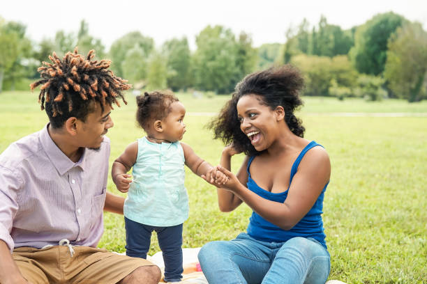 szczęśliwa afrykańska rodzina bawiąca się w publicznym parku - matka i ojciec z córką cieszący się razem podczas weekendu na świeżym powietrzu - rodzice kochają i koncepcja dnia matki - family american culture african culture black zdjęcia i obrazy z banku zdjęć