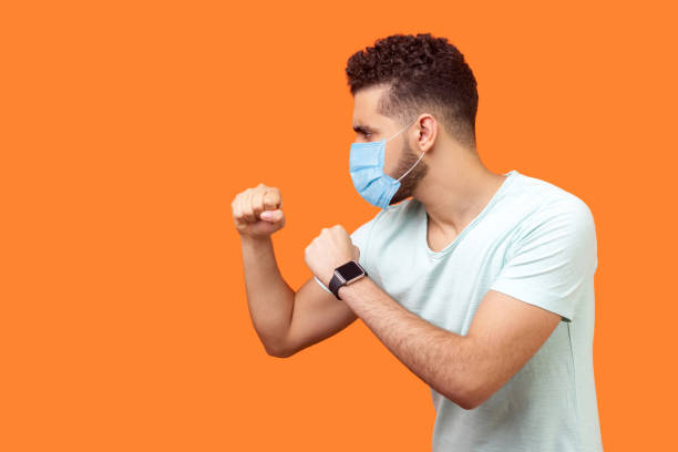boxing and self-defence. side view of aggressive man with surgical medical mask keeping fists clenched, ready for fight. empty copy space on left for text. - wall profile imagens e fotografias de stock