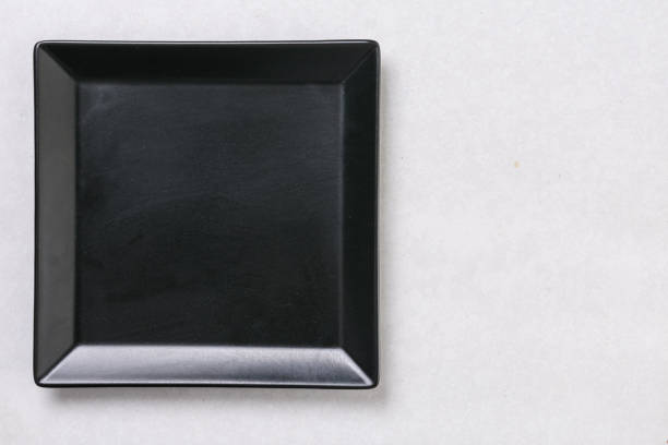 istock Flat lay above black square plate on the white marble table background 1216217426
