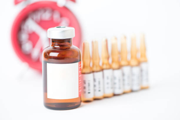 istock Injection vials and ampules on red alarm clock 1216217525