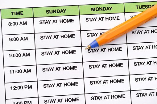 Stay at home written in every day on a daily schedule. Coronavirus outbreak and pandemic concept. Close up.