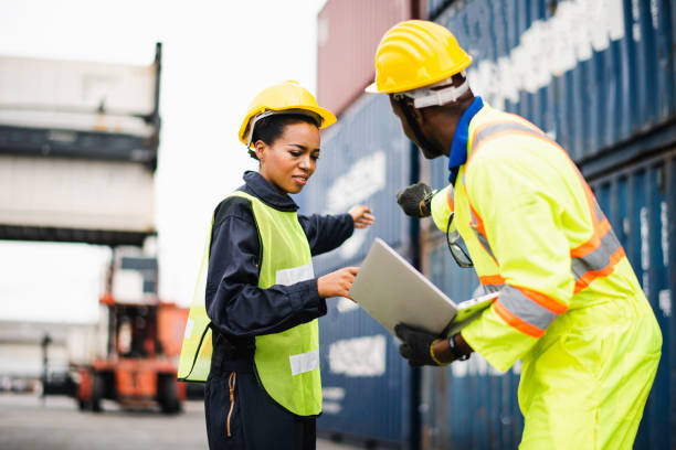 istock Young African american men and woman worker Check and control loading freight Containers by use computer laptop at commercial shipping dock felling happy. Cargo freight ship import export concept 1216219256