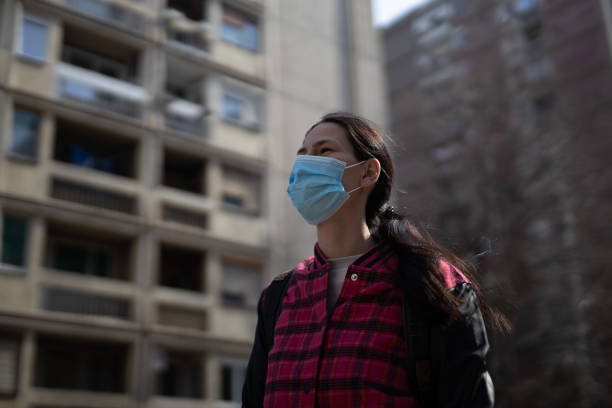 istock Young woman with surgical mask walking between skyscrapers 1216219259