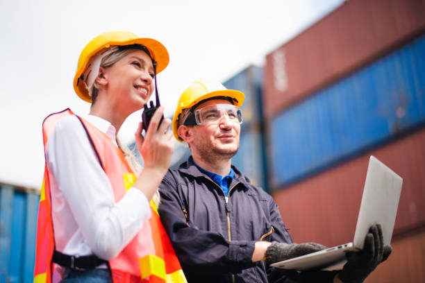 istock Young Caucasian man and woman worker Check and control loading freight Containers by use computer laptop and radio at commercial shipping dock felling happy. Cargo freight ship import export concept 1216219470