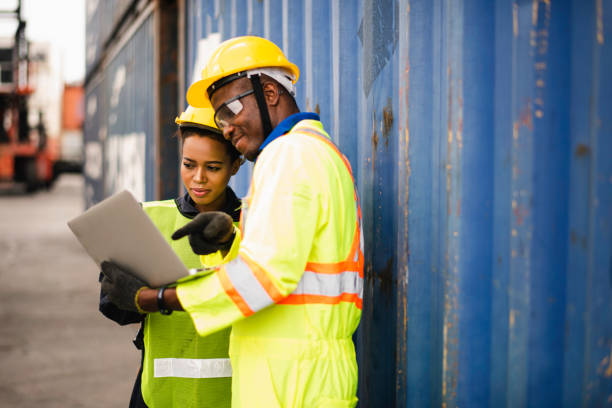 istock Young African american men and woman worker Check and control loading freight Containers by use computer laptop at commercial shipping dock felling happy. Cargo freight ship import export concept 1216219699
