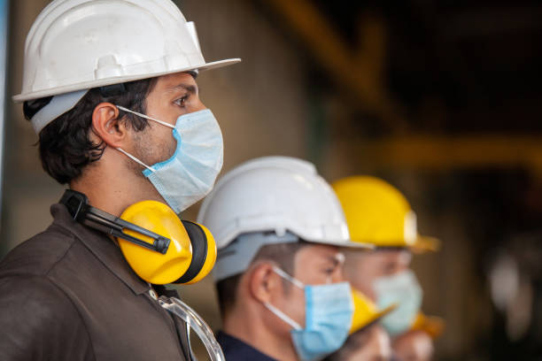 los trabajadores usan máscaras faciales protectoras para la seguridad en la fábrica industrial de la máquina. - safety sign protective workwear factory fotografías e imágenes de stock