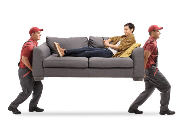 istock Movers carrying a sofa and a man sitting on the sofa with a mobile phone 1216223859