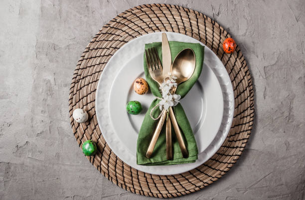 istock Easter table setting. Empty plates with green linen napkin and golden cutlery on concrete background. Top view. Flat lay. Copy space. 1216224081