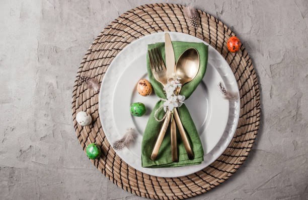 istock Easter table setting. Empty plates with green linen napkin and golden cutlery on concrete background. Top view. Flat lay. Copy space. 1216224091